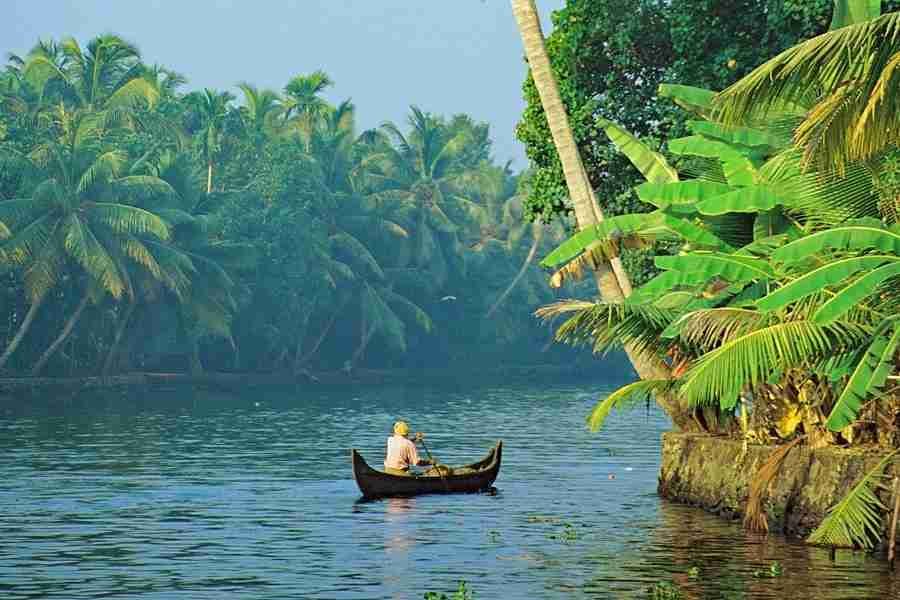 Traditional wooden boat sailing through the tropical Kerala backwaters