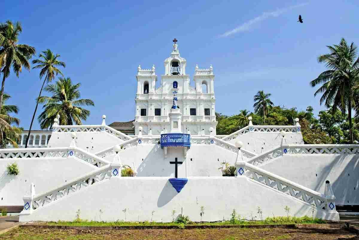 Historic white church with twin towers in Kerala under a clear blue sky