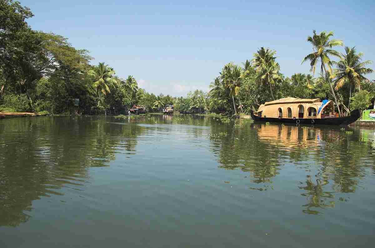 Traditional Kerala houseboat cruising through peaceful backwaters surrounded by greenery